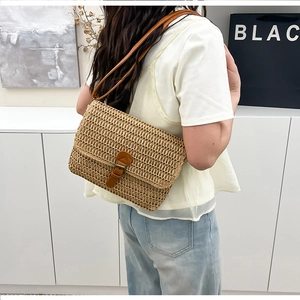 Détail d'un sac bandoulière en paille tressée avec fermoir en cuir brun et bandoulière