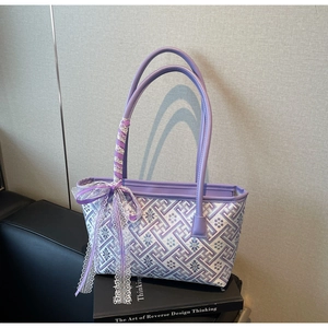Close-up of geometric pattern bucket bag with purple leather handles and lace bow
