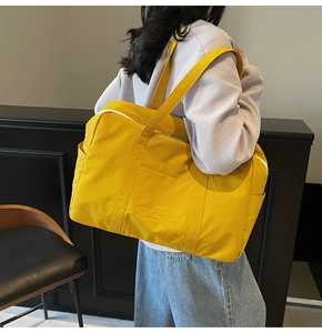 Close-up of bright yellow large capacity tote bag with embossed text and side pocket
