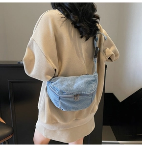 Rear view of model wearing a blue denim crescent chest bag with adjustable strap