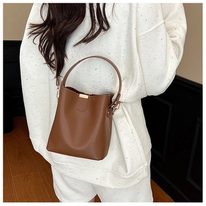 Brown bucket bag styled with a minimalist hoodie, showcasing the crossbody strap and handle