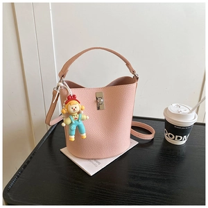 Pink lychee grain bucket bag featuring a colorful cartoon charm and silver twist lock detail