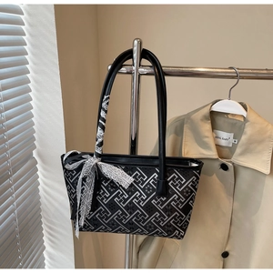 Detail of black geometric pattern tote bag with decorative lace scarf on a hanger