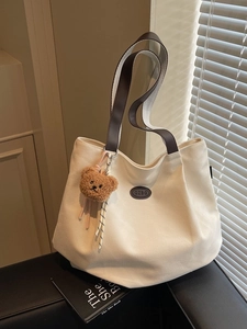 Sac cabas minimaliste en toile beige avec lanières en cuir marron et breloque ours