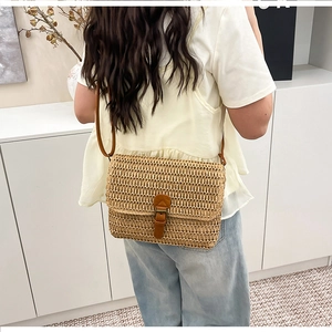 Détail d'un sac bandoulière vintage en paille avec bandoulière en cuir brun et boucle