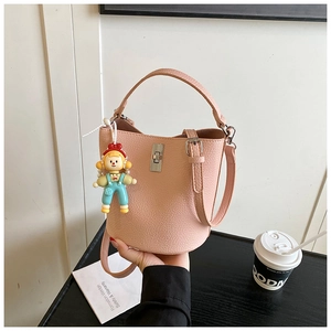 Detailed macro view of pink litchi grain bucket bag with silver clasp and cartoon charm