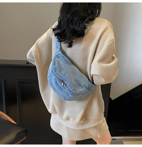 Close-up of light blue denim crossbody chest bag with silver zippers shown on back