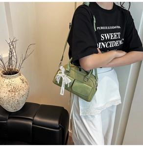 Detail of green woven bowling bag featuring a white lace bow and adjustable strap