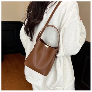Detailed view of a vintage brown leather bucket bag with elegant metal clasp and shoulder strap