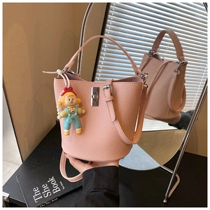 Detail of pink lychee leather bucket bag with silver turn-lock and cute doll charm