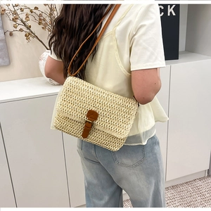 Détail du tissage en paille et de la bandoulière en cuir brun du sac bandoulière