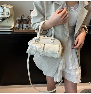 Detail of cream bowling bag with lace bow charm and textured patchwork fabric
