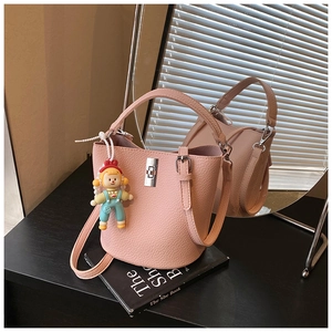 Close-up of pink bucket bag in lychee leather with silver clasp and cartoon charm