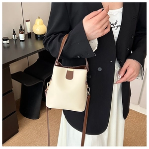 Minimalist beige bucket bag with brown contrast straps and gold metal hardware detail