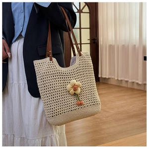 Dettaglio della borsa tote intrecciata con tracolla in pelle e ciondolo a girasole