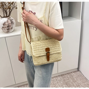 Détail d'un sac bandoulière beige en paille tressée avec lanière en cuir marron