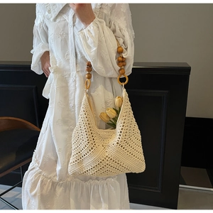 Details der handgewebten Strohtasche mit Holzperlenriemen und Lochmuster-Textur