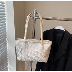 Detailed view of beige jacquard bucket bag with geometric patterns and lace bow
