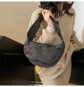 Detail of a crescent denim crossbody bag showing the adjustable strap and buckle closure
