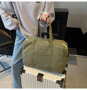 Army green nylon travel bag placed on a white suitcase showing spacious structure