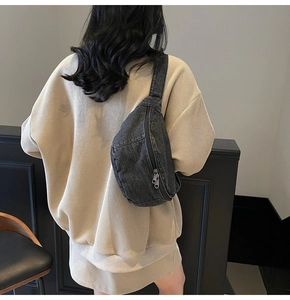 Detail view of washed denim chest bag worn by a model in a minimalist indoor setting