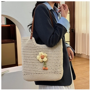 Dettaglio della borsa tote intrecciata con girasole e manici in pelle marrone