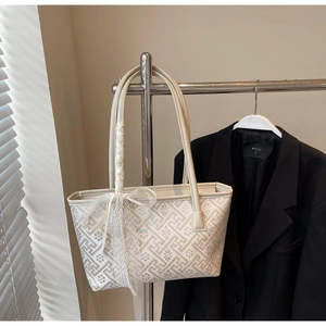 Detail of cream tote bag with floral embroidery and lace ribbon on a metal hanger