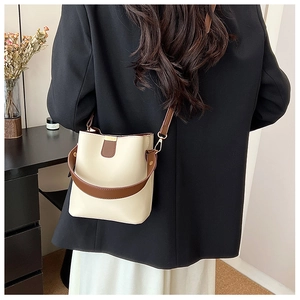 Detailed back view of a minimalist two-tone bucket bag with adjustable brown shoulder strap