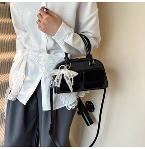 Chic black bowling bag with lace bow and pearl pendant shown on a model