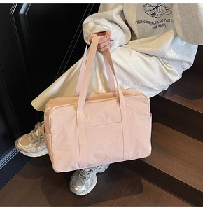 Detail of light pink large capacity travel tote bag with side pocket and zipper closure