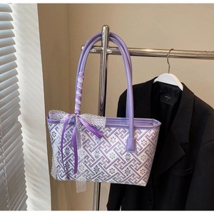 Close-up of jacquard tote bag with purple geometric pattern and white lace handle details