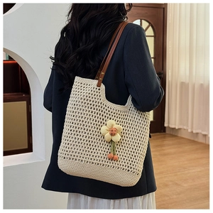 Dettaglio della borsa tote a rete intrecciata con fiore giallo e manici in pelle marrone