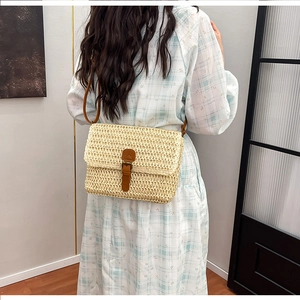 Détails du tissage en paille et de la lanière en cuir marron d'un sac bandoulière de plage