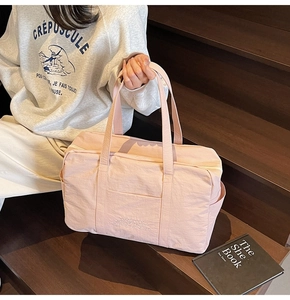 Detailed shot of a pink nylon travel bag with large front pocket and double handles