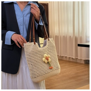 Dettaglio della borsa tote in maglia traforata con ciondolo a fiore 3D e manici in pelle