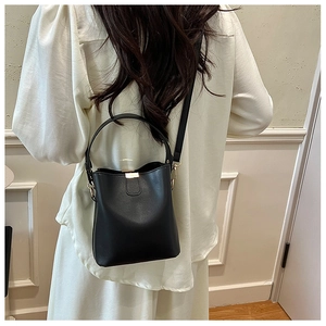 Detail of black leather bucket bag featuring gold buckle and adjustable shoulder strap