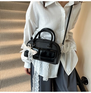Detail of black bowling bag with woven texture and a large white lace bow accent