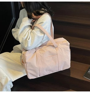 Lifestyle view of a large light pink tote bag on wooden stairs with branded text