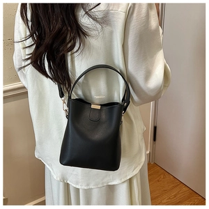Lifestyle shot of black leather bucket bag worn as an underarm bag by a model