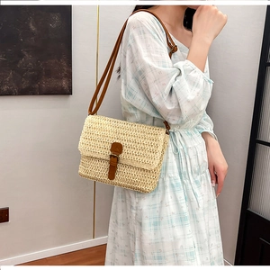 Détail du sac bandoulière en paille tressée beige avec sangle et boucle en cuir marron