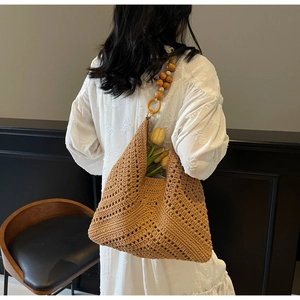 Detail einer handgewebten Stroh-Tote-Bag mit dekorativem Griff aus Holzperlen
