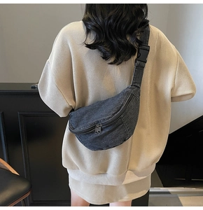 Detail of dark grey denim crossbody bag featuring durable double zippers and wide strap