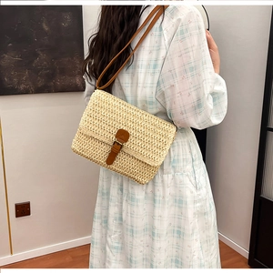 Détail du sac bandoulière carré en paille avec sangle en cuir brun et boucle métal