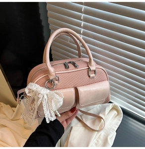 Close-up of pink woven handbag with white lace bow, pearl charm and silver zipper