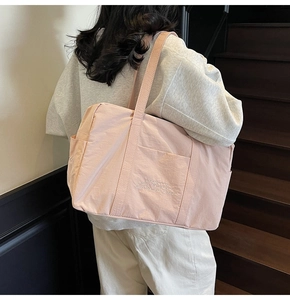 Close-up of a light pink tote bag with white embroidery on high-quality nylon fabric