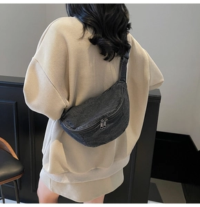 Rear view of a model wearing the dark gray denim crescent crossbody bag with nylon strap