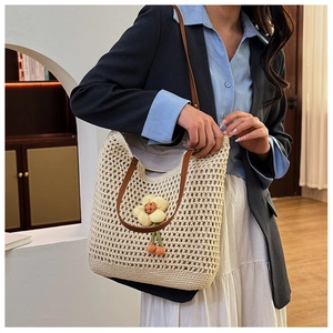 Dettaglio macro della borsa tote in beige intrecciato con maglia e tracolla in pelle
