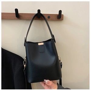 Detail of black matte bucket bag with golden buckle and detachable shoulder strap