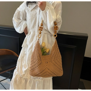 Detail der handgewebten Strohtasche mit hohlem Wellenmuster und Perlen aus Holzdekor