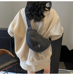 Detail of grey denim crescent sling bag with adjustable strap shown on model back